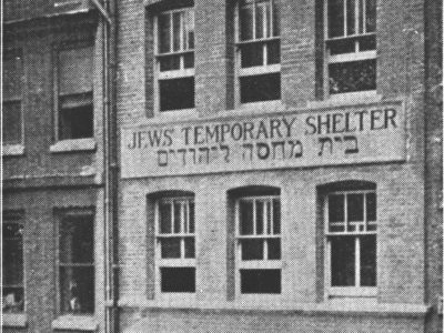 Black and white image of a tall building with a sign saying Jews Temporary Shelter