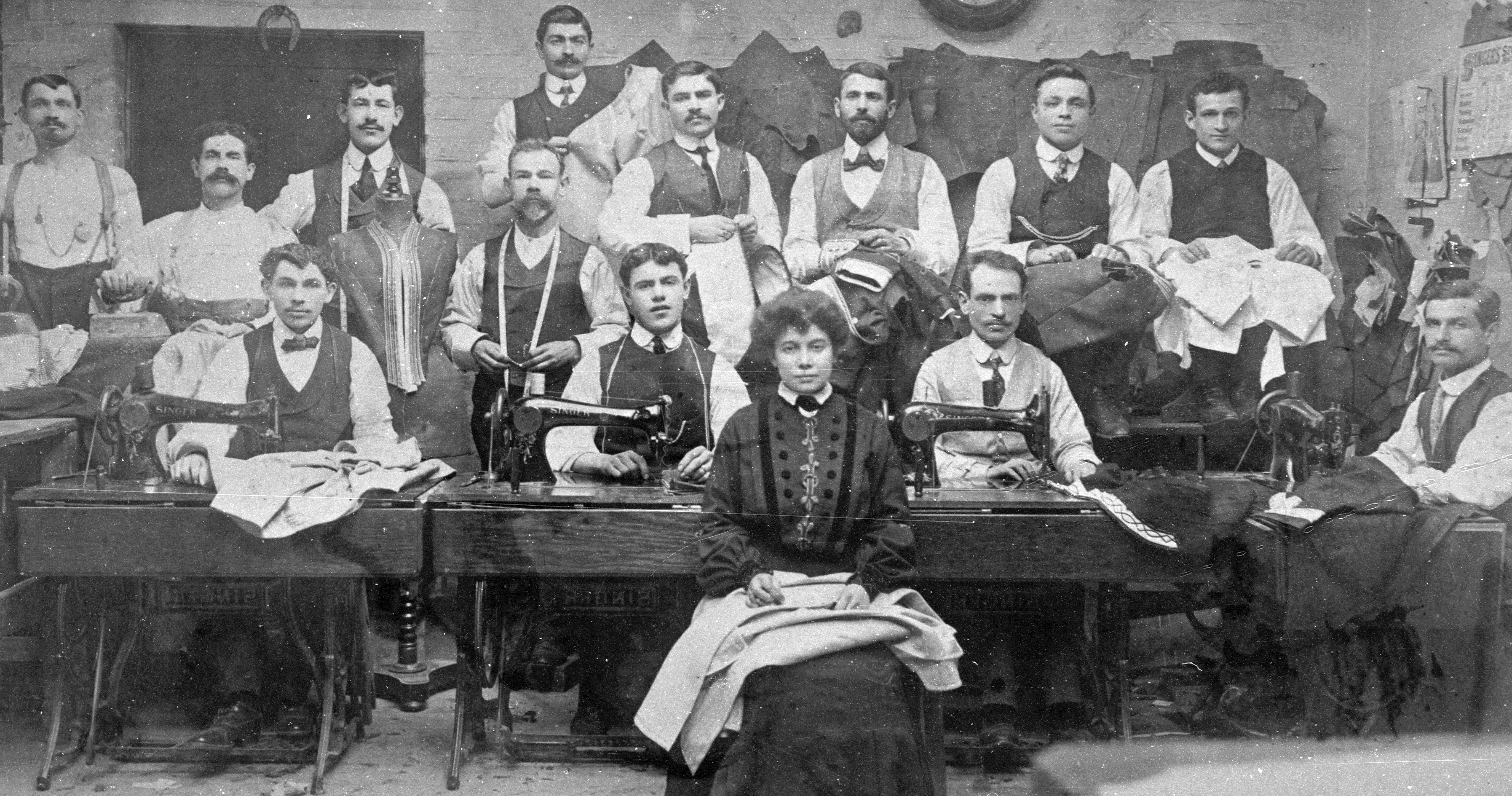 B&w photo of sewing workshop woman in front and men behind