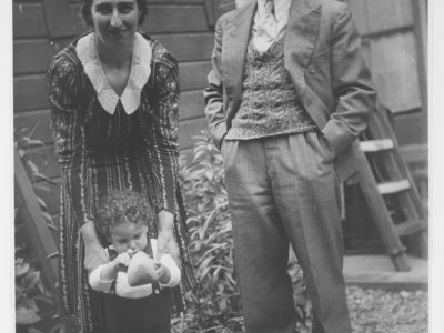 A mother and father with their young son, who is holding a wooden shoe