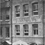 A black and white photograph of a five-storey building with the name 'Jewish Temporary Shelter' written on the front of the building.