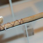 wooden handle with string wrapped around, with bristles at one end