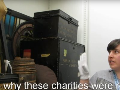Woman points at Charity Deed Box.