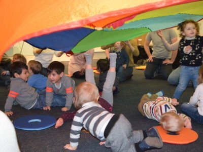 children crawling under colourful parachute