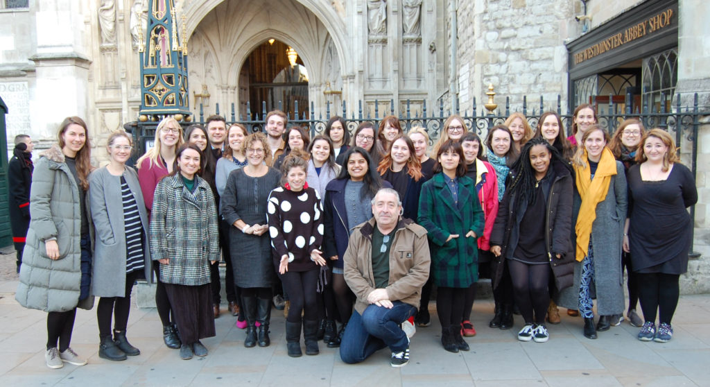 A large group of mixed adults standing outside of Westminster Abbey gates