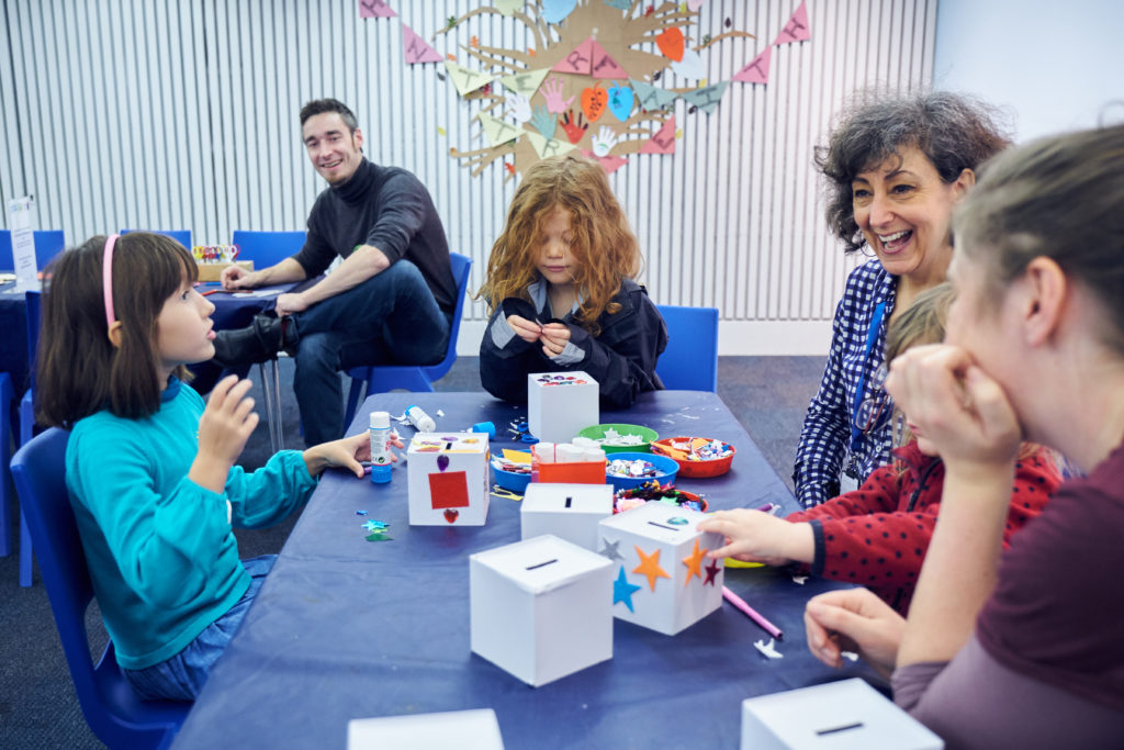 Children and adults sat at a table doing arts and crafts