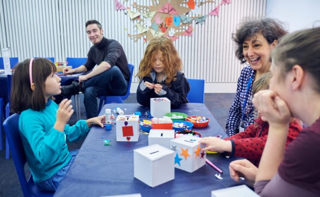 Children and adults sat at a table doing arts and crafts