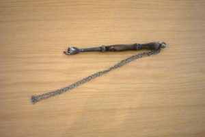 A wooden stick with a chain on a wooden table 