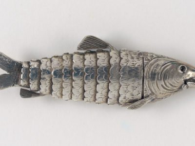 A silver spice box in the shape of a fish with fins and scales