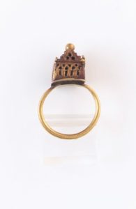 A gold ring with embellishment on the top 