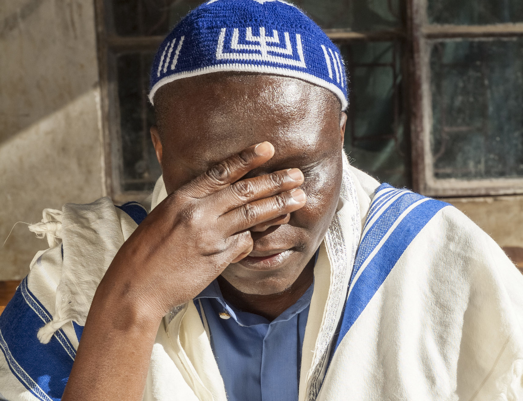Man praying, wearing prayer shawl and skull cap.