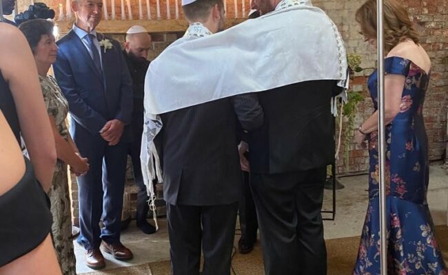 Two men getting married under a Chuppah.