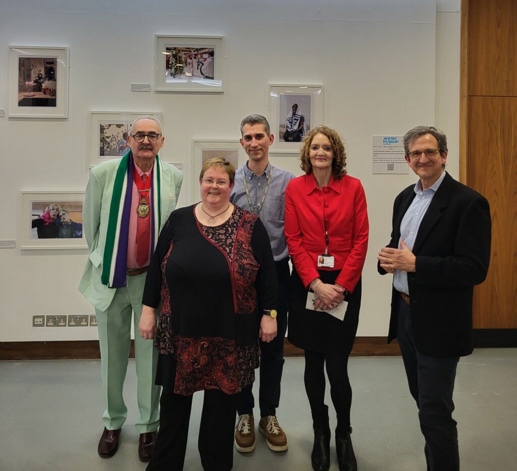 Image featuring camden councillors and Jewish Museum staff standing in a gallery with various images of Jewish life in the background.