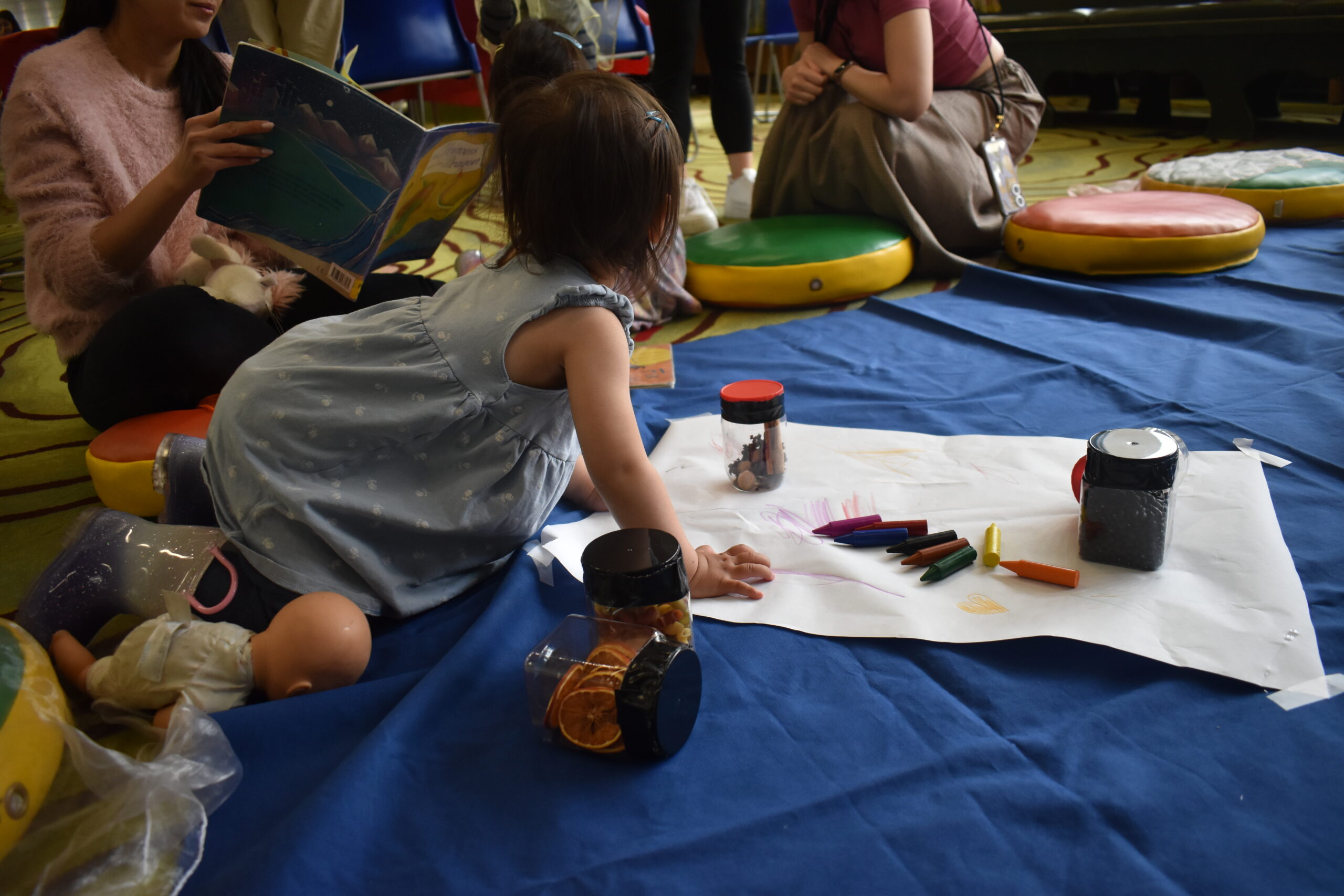 a baby playing with crayons and harvest-themed sensory toys